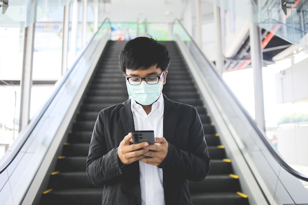 Trabajador autónomo asiático con mascarilla quirúrgica yendo a trabajar por la mañana en el metro