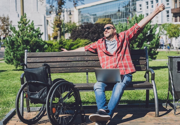 Foto trabajador autónomo con discapacidad física que usa silla de ruedas trabajando en el parque