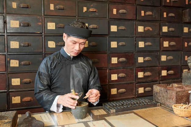 Trabajador de boticario triturando ingredientes de medicina seca