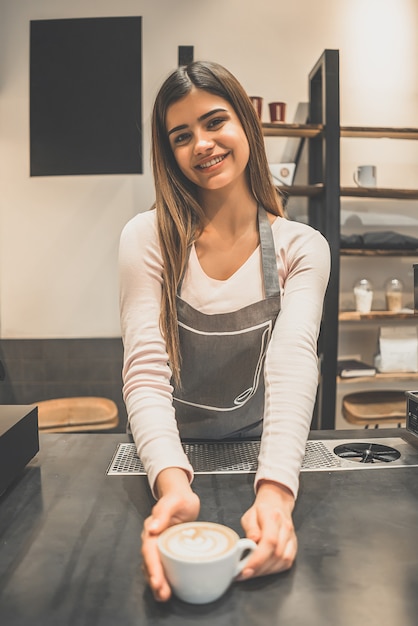 El trabajador de la cafetería sosteniendo una taza de café