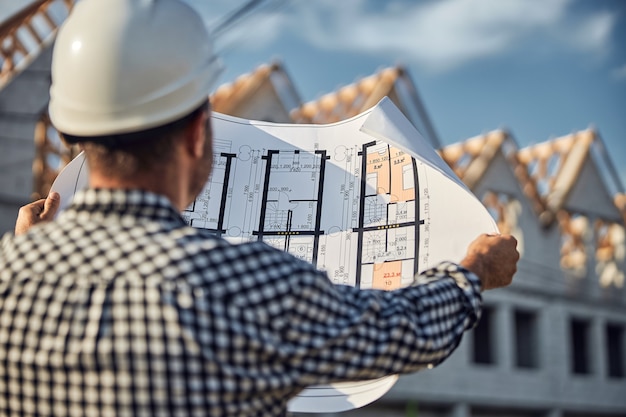 Foto trabajador calificado de un sitio de construcción mirando el plano