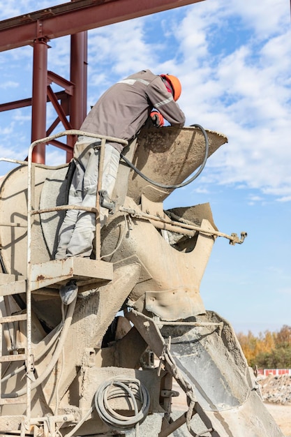 Un trabajador en un camión hormigonera se prepara para hormigonar una estructura de hormigón armado. Equipo para la entrega de hormigón al sitio de construcción.