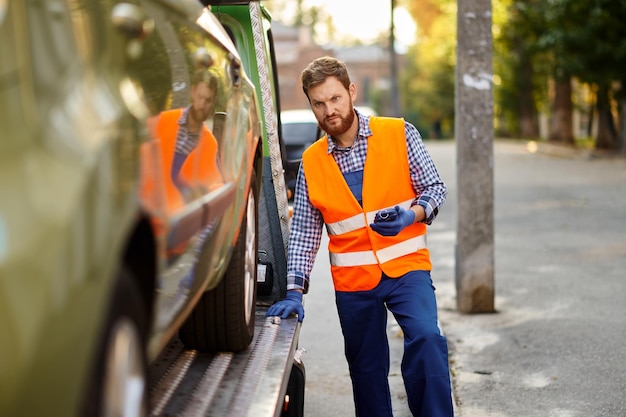 Trabajador de camión de remolque comprobando la precisión de carga del coche