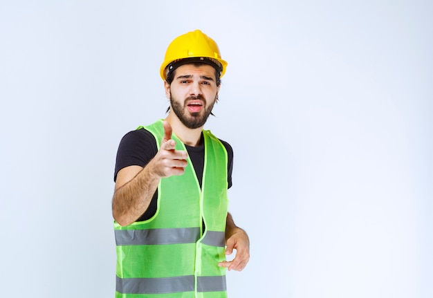 Trabajador en casco amarillo notando a la persona que está adelante.