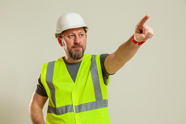 Foto un trabajador con un chaleco y un casco de construcción blanco muestra gestos con las manos en diferentes poses en