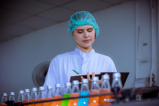 Trabajador científico en una fábrica de bebidas en botella con uniforme de seguridad, máscara facial, discusión y trabajo para comprobar la calidad de la bebida.