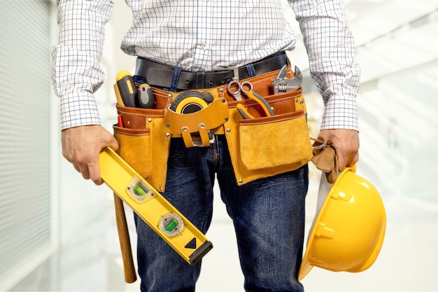 Trabajador con un cinturón de herramientas. Aislado sobre fondo.