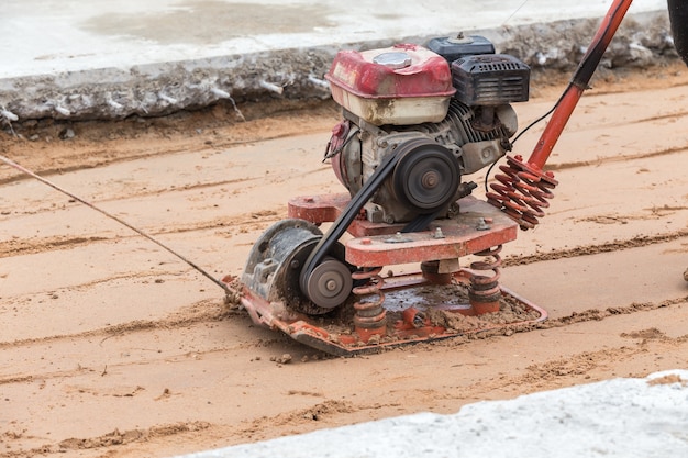 Trabajador con compactadores de suelo en sitio de construcción