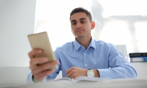 Trabajador concentrado usando teléfono inteligente chateando o navegando en internet