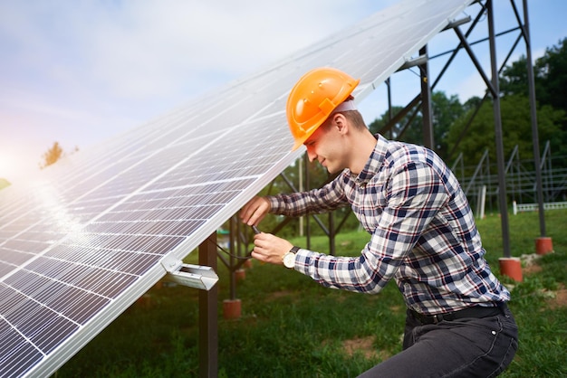 Trabajador conecta paneles solares en una plantación verde Construcción de viviendas