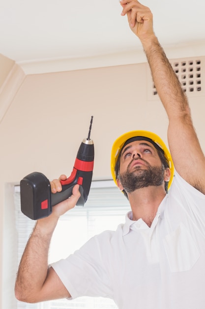 Trabajador de la construcción, agujero de perforación en el techo