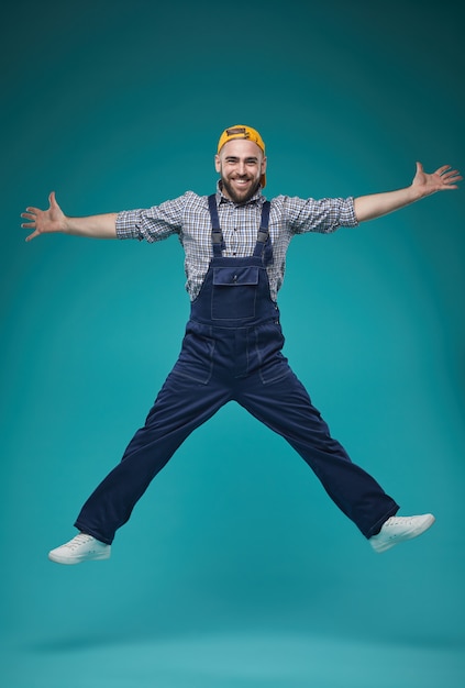 Trabajador de la construcción alegre saltando sobre azul