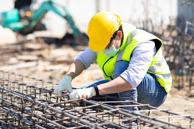 Trabajador de la construcción asiática en obra. Fabricación de barra de refuerzo de acero. usar mascarilla quirúrgica durante el coronavirus y el brote de gripe