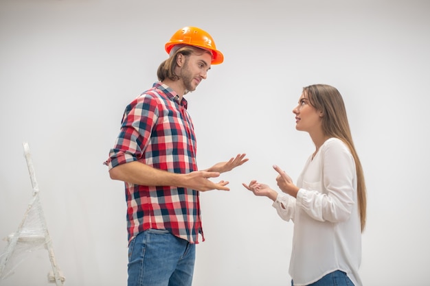 Trabajador de la construcción en casco naranja hablando con un cliente