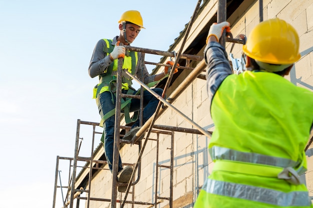 Foto trabajador de la construcción con cinturón de arnés de seguridad durante el trabajo en lugar alto, concepto de edificio residencial en construcción.