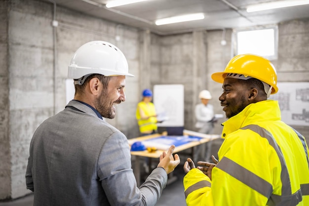 Trabajador de la construcción e ingeniero estructural discutiendo sobre un nuevo proyecto de construcción