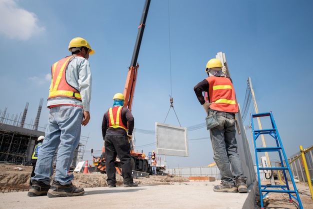 Foto trabajador de la construcción e ingeniero mirando grúa móvil levante muro de hormigón prefabricado