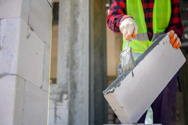 Trabajador de la construcción Estamos enyesando el mortero adhesivo que utiliza hormigón ligero para la construcción. Técnicas de aplicación de mortero adhesivo en obra.