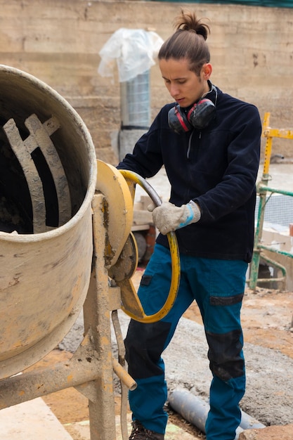 Trabajador de la construcción haciendo hormigón en la mezcladora de cemento en el sitio de construcción