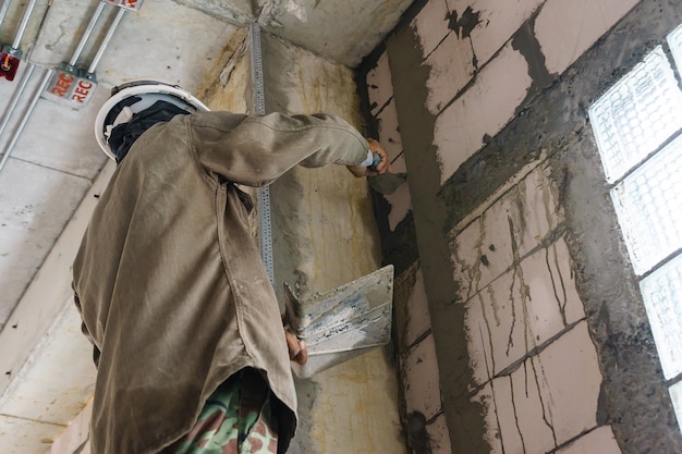 Trabajador de la construcción con herramientas de enlucido de pared