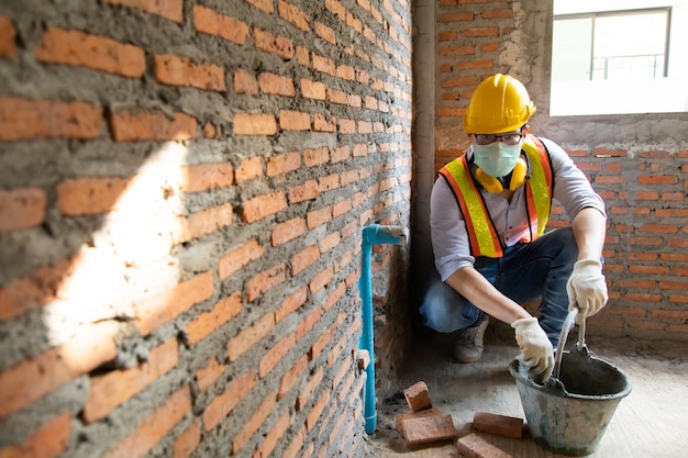 Trabajador de la construcción del hombre asiático que sostiene el tubo y que trabaja en el sitio.