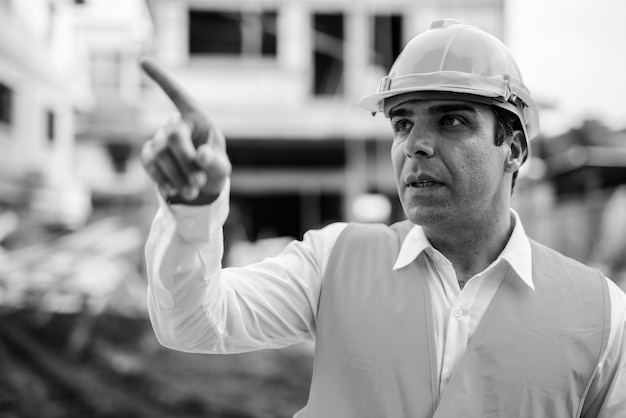 Trabajador de la construcción del hombre persa guapo en la construcción sit