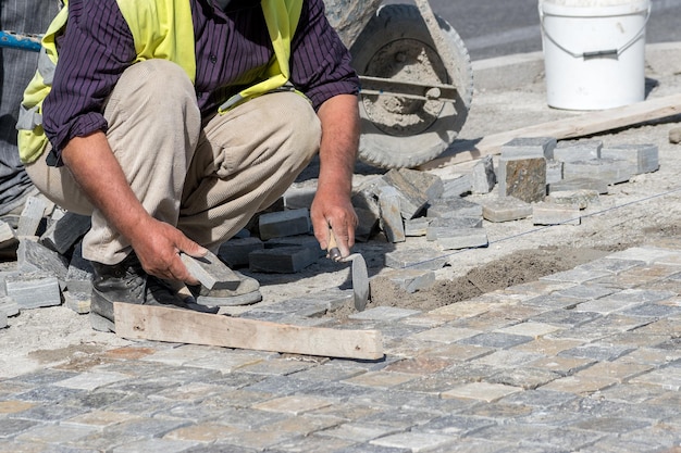Trabajador de la construcción instalando bloques de piedra en la calle