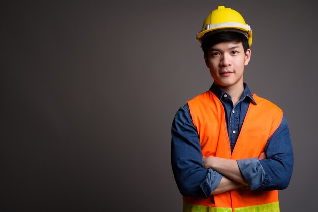 Trabajador de la construcción joven apuesto hombre asiático en gris