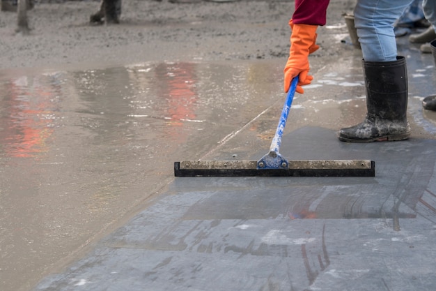 Trabajador de la construcción con llana de hormigón mojado en la parte superior de la losa de piso nuevo constructio