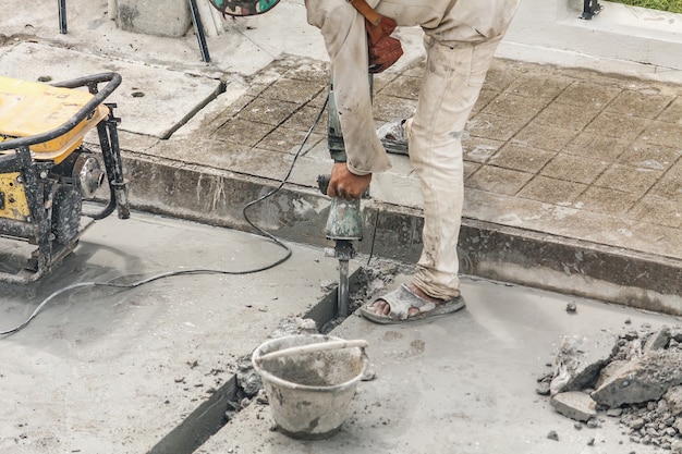 Foto trabajador de la construcción con martillo neumático de perforación de superficie de hormigón