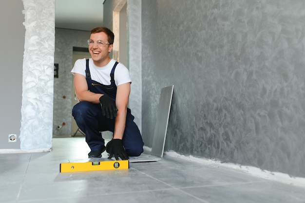 Un trabajador de la construcción masculino instala una gran baldosa cerámica.