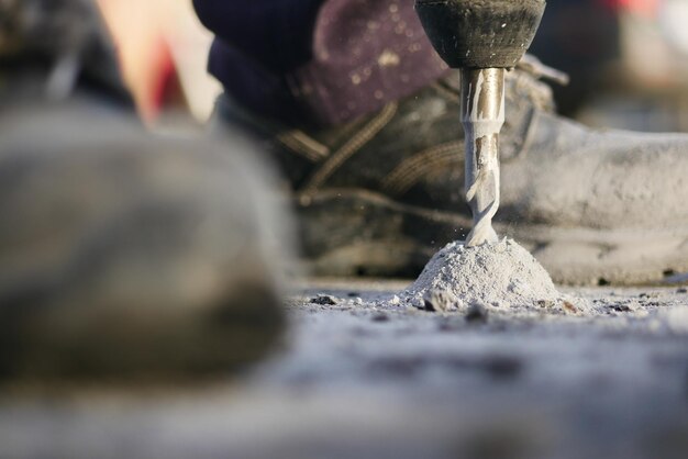 Un trabajador de la construcción perfora el hormigón en un sitio de construcción