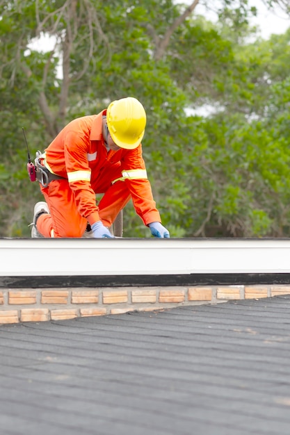 Trabajador de la construcción poniendo el techo de asfalto