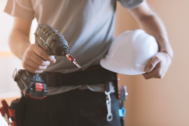 Trabajador de la construcción posando con casco de seguridad y taladro