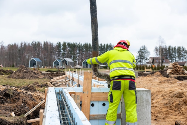 Trabajador de la construcción que opera con precisión la bomba de hormigón en los cimientos de un nuevo sitio de construcción