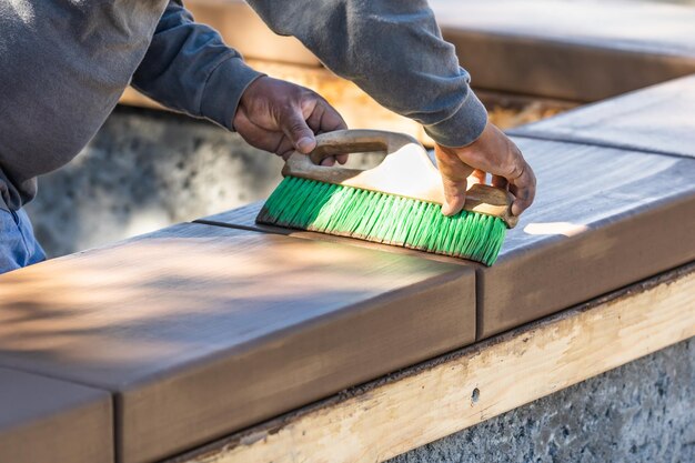 Trabajador de la construcción que usa un pincel en el cemento húmedo que forma alrededor de la nueva piscina