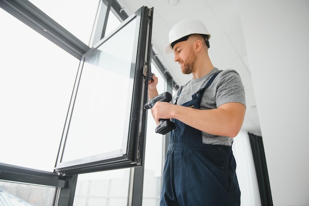 Trabajador de la construcción reparando una ventana de plástico con un destornillador en el interior, espacio para texto. Diseño de pancartas