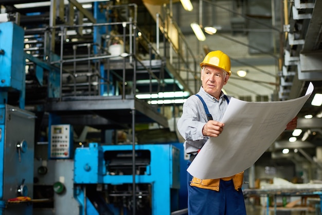 Trabajador de la construcción senior con planos de planta