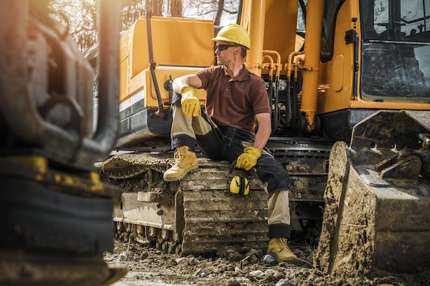 Foto trabajador de la construcción sentado en una excavadora