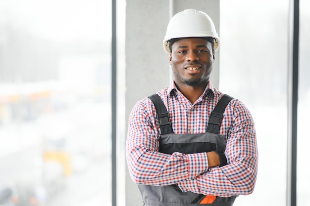 Trabajador de la construcción sonriente con los brazos cruzados en el sitio