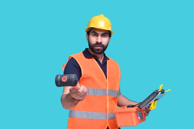 Trabajador de la construcción sosteniendo una caja de herramientas y mostrando un martillo modelo paquistaní indio