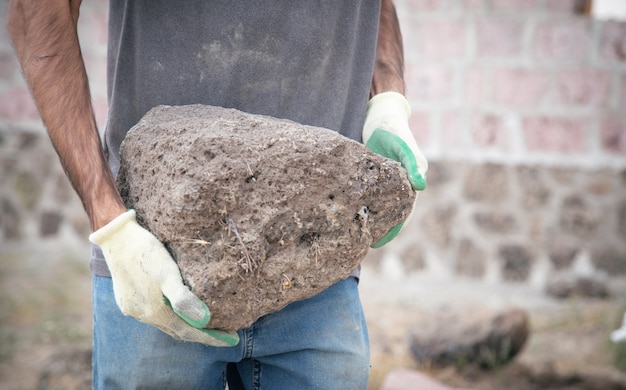 Foto trabajador de la construcción sosteniendo una piedra de cuarzo.