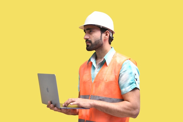 Trabajador de la construcción sosteniendo un portátil y mirando a otro lado modelo paquistaní indio