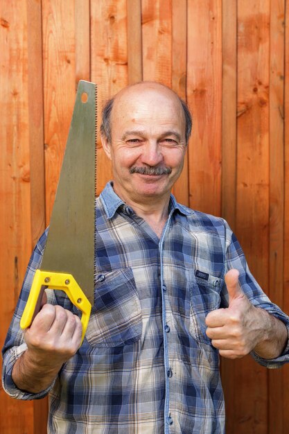Trabajador de la construcción sosteniendo una sierra y mostrando su aprobación