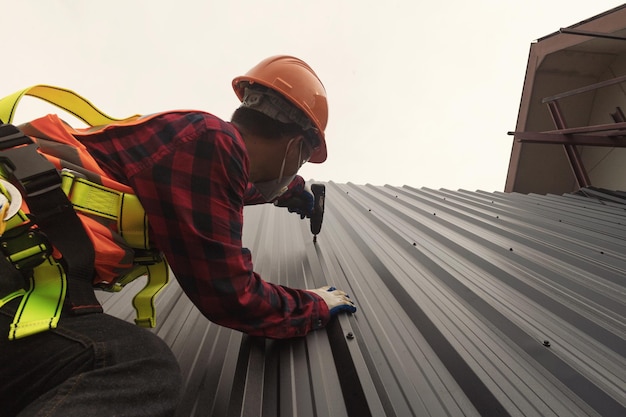 El trabajador de la construcción del techador instala un techo nuevo, herramientas para techos, taladro eléctrico usado en techos nuevos con chapa metálica.