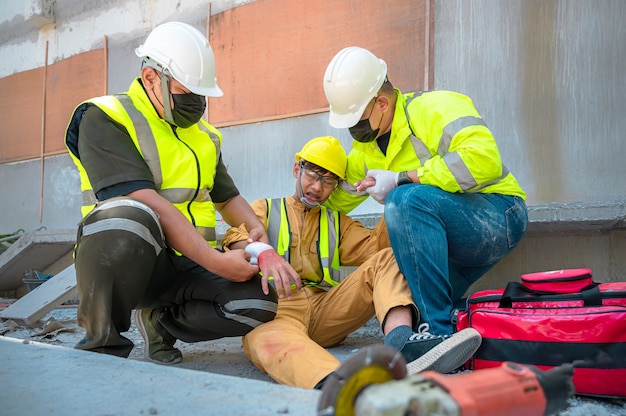 Trabajador de la construcción tiene un accidente en un sitio de construcción. Los ingenieros de ayuda de emergencia brindan primeros auxilios a los trabajadores de la construcción en accidentes. El equipo de seguridad ayuda a un trabajador de la construcción que tiene un accidente.