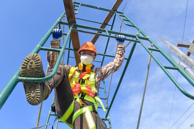 Trabajador de la construcción con trabajo de seguridad en uniforme alto en andamios en el sitio de construcción durante la puesta de sol, trabajando en equipos de altura.