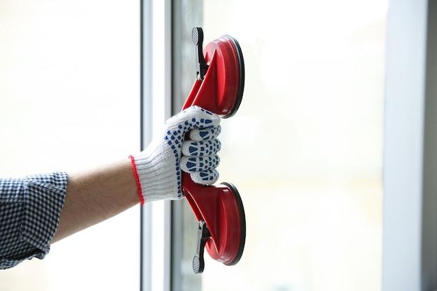 Foto trabajador de la construcción usando elevador de succión durante la instalación de ventanas en el interior de primer plano