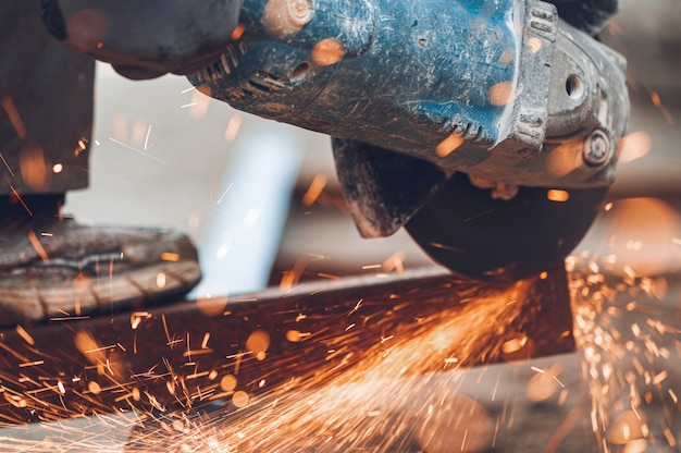 Trabajador de la construcción utilizando Angle Grinder corte de metal en el sitio de construcción.