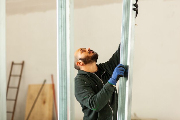 Trabajador construye una pared de placas de yeso.